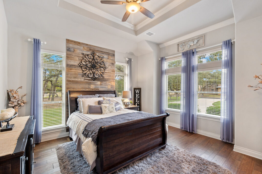 Gray shag area rug layered over hardwood flooring in a primary bedroom with a dark wood sleigh bed