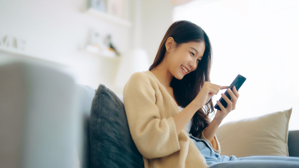 Woman smiling while checking a flooring warranty on her phone at home